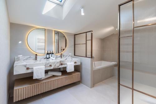 a bathroom with a sink and a tub and a mirror at Villa Delta - Parkhotel Delta in Ascona