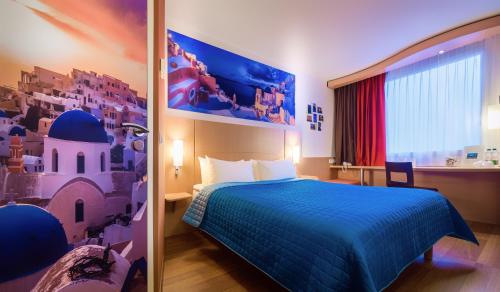 ワルシャワにあるイビス ワルシャワ レドゥータの青いベッドと窓が備わるホテルルームです。