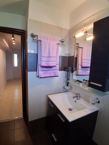 a bathroom with a sink and a mirror and purple towels at Οcalia Apartment in Petrokhórion