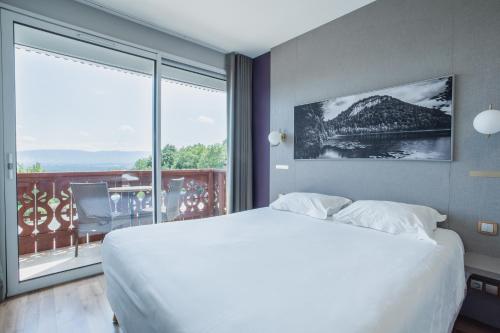 a bedroom with a large white bed and a balcony at Hôtel-Restaurant Bois Joly in Crozet