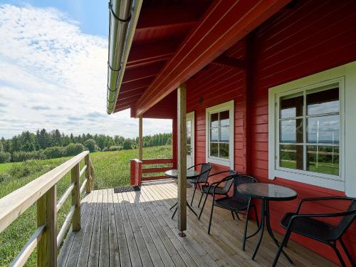 a porch of a red house with chairs and a table at Itärajan Helmi in Tohmajärvi