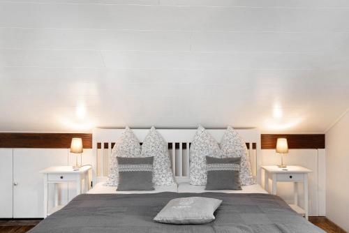 a white bedroom with a large bed with two tables at Schwarzwaldtani - Dörfle in Weier