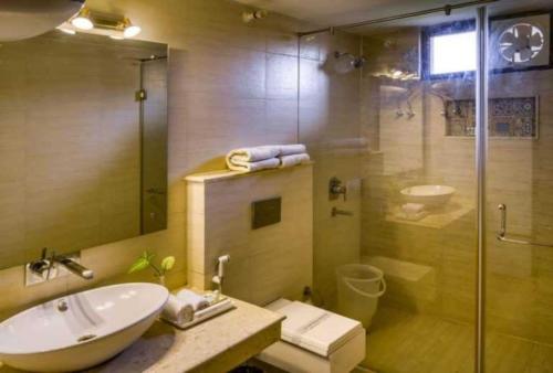 a bathroom with a sink and a glass shower at Sunday Alaya Resort by CheckIn, Jim Corbett in Belparāo
