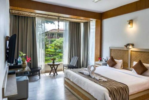 a bedroom with a large bed and a large window at Sunday Alaya Resort by CheckIn, Jim Corbett in Belparāo