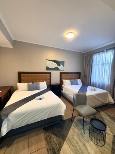 ein Hotelzimmer mit zwei Betten und einem Stuhl in der Unterkunft CapePod City Centre in Kapstadt
