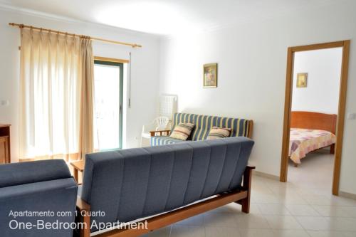 sala de estar con sofá azul y cama en Akisol Armação Pera Beach, en Armação de Pêra