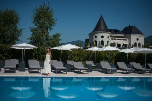 a woman in a white dress standing next to a swimming pool at Lopota Lake Resort & Spa in Napareuli