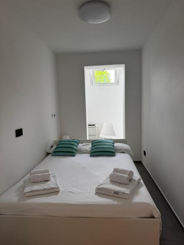 a white bedroom with a large bed with green pillows at Villa Lavinia a Colico in Colico