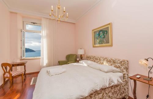 a bedroom with a bed with a chandelier and a window at Luxury Seafront Apartment Banje in Dubrovnik
