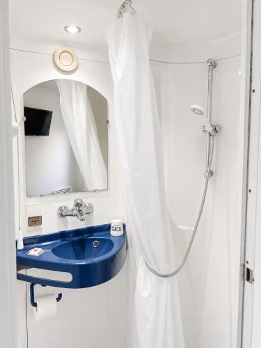 a bathroom with a blue sink and a shower at Hôtel Gex in Gex