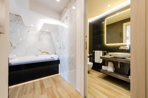 a bathroom with a tub and a sink and a mirror at Municipio Luxury Suite in Naples