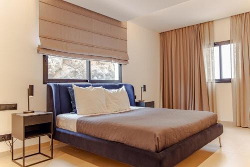 a bedroom with a bed with a blue headboard and a window at Nusa Apartments Monte Cara in Mindelo