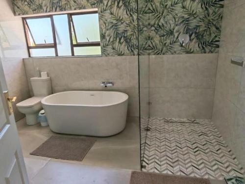 a bathroom with a bath tub and a toilet at Pearl Vista in Somerset West