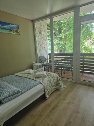 a bedroom with a bed and a balcony with windows at Sunrise Apartments 9 in Juodkrantė