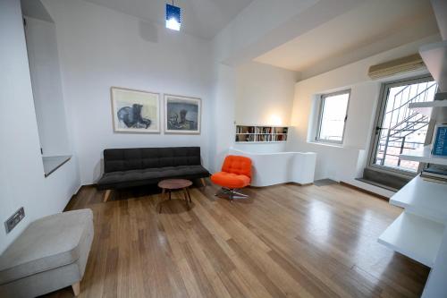 a living room with a black couch and an orange chair at Acropolis Neoclassic Elegance in Athens