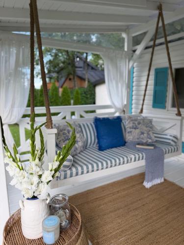 a porch swing with a couch and flowers on it at Domek holenderski Hampton in Dominice
