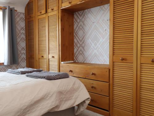 a bedroom with a bed and wooden cabinets at 31 Ffordd Y Maer in Pwllheli