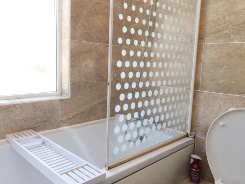 a shower with a glass partition in a bathroom at 31 Ffordd Y Maer in Pwllheli