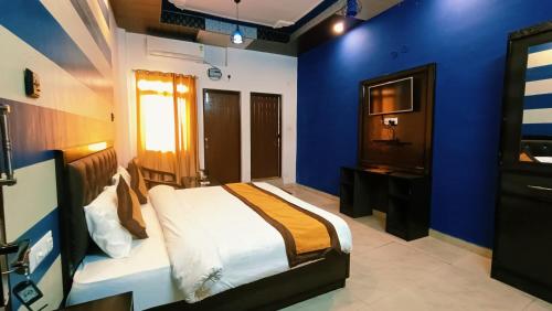 a blue bedroom with a bed and a television at Hotel Bhagirathi in Tehri-Garhwāl