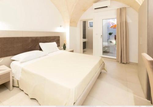 a white bedroom with a large white bed and a window at Vie Del Salento in San Pancrazio Salentino