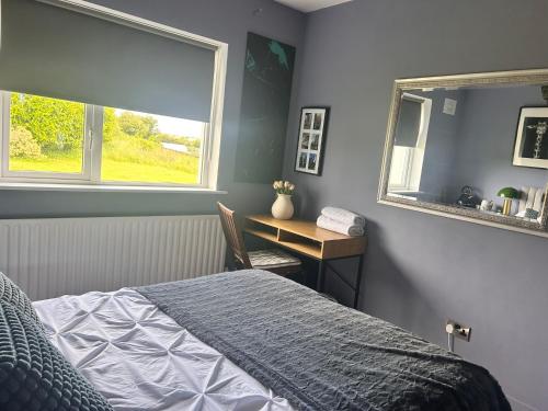 a bedroom with a bed and a desk and a window at Follies Garden Room in Dungarvan