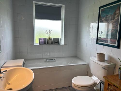 a bathroom with a tub and a toilet and a sink at Follies Garden Room in Dungarvan