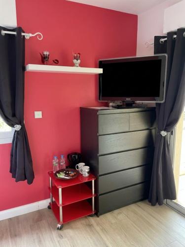 ein Zimmer mit Fernseher und roter Wand in der Unterkunft La Villa des Demoiselles - 2 chambres communicantes in Bourg-Achard
