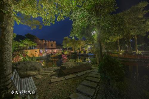 a park with a bench and a river at night at Rainbow SpringYU B&B in Nanzhuang