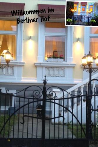 a white building with a balcony and a fence at Berliner Hof in Dallgow