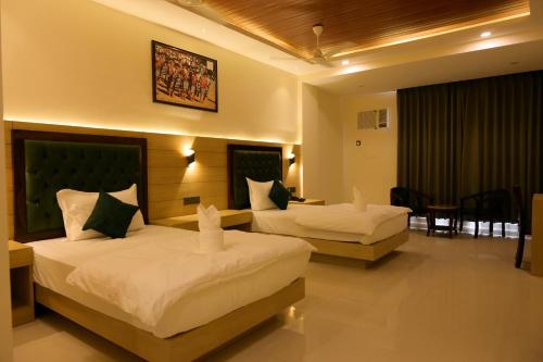 a hotel room with two beds and a table at Hotel Grand Mayfair in Dimapur