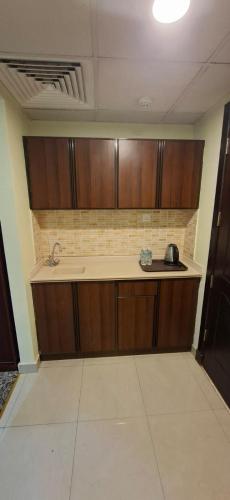 a kitchen with wooden cabinets and a counter top at فندق فيصل الصفوة in Al Khansāk