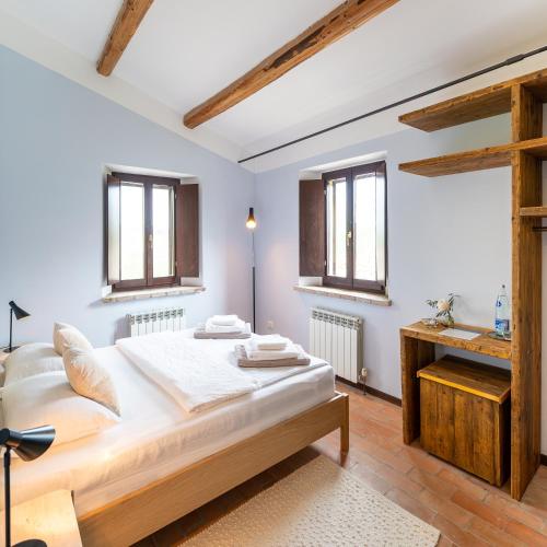 a bedroom with a large bed and two windows at Rifugio Vita Luminosa in Montecarotto