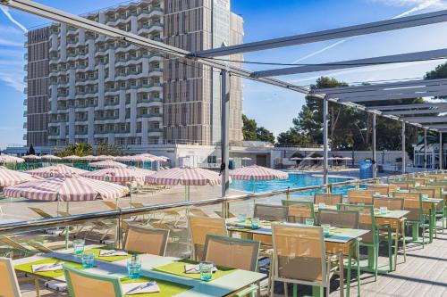a row of tables with umbrellas and a pool at SOL by Meliá Barbados in Magaluf