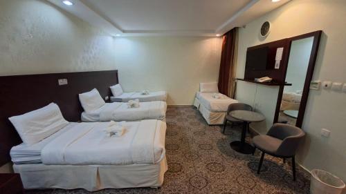 a hotel room with two beds and a mirror at فندق فيصل الصفوة in Al Khansāk