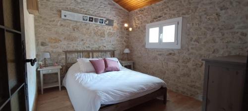 a bedroom with a bed with white sheets and pink pillows at Gîte Maelga in Cartelègue