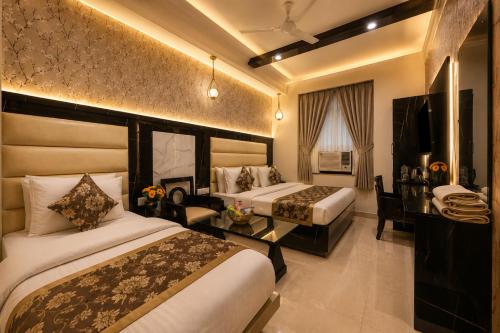 a hotel room with two beds and a table at Hotel Baba Deluxe near New Delhi Railway Station and City Center -By RCG Hotels in New Delhi