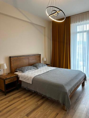 a bedroom with a large bed and a chandelier at Sol's M2 White Modern Apartments in Tbilisi City