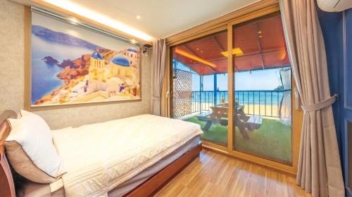 a bedroom with a bed and a large window at Goseong CNBLUE Oceanview Pension in Goseong
