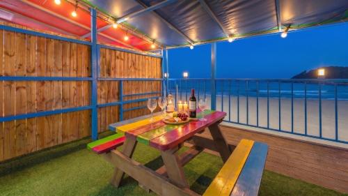 a table with wine glasses and a bottle on a balcony at Goseong CNBLUE Oceanview Pension in Goseong