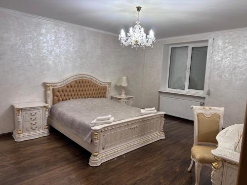 a bedroom with a white bed and a chandelier at Оксамитове ретро in Ternopil