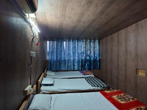 two beds in a small room with a window at Terrace Camp inn in Tiruchirappalli
