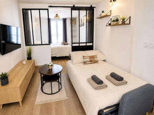 a room with two beds and a table in it at La Suite Prestige in Château-Thierry