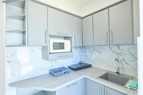 a white kitchen with a sink and a microwave at Hotel Silver in Hajdúszoboszló