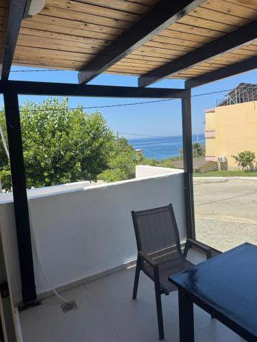 a chair on a balcony with a view of the ocean at 44 suites Lygia in Paralia Vrachou
