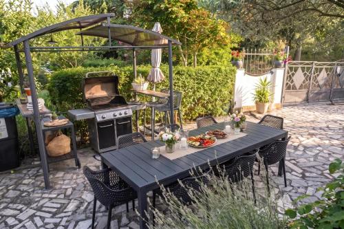 a table in a backyard with a grill and a table with food at Villa Bazilika in Sečovlje