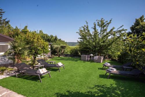 a yard with lounge chairs on the grass at Villa Bazilika in Sečovlje