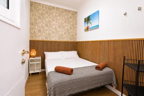 a small bedroom with a bed and a wooden wall at Kite & Surf Nomad House in Las Palmas de Gran Canaria