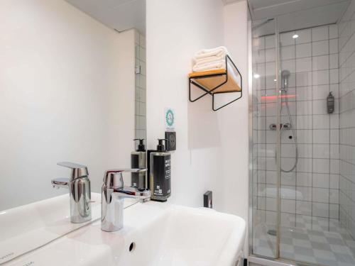 a white bathroom with a sink and a shower at Ibis Styles Paris Gare de l'Est Magenta in Paris
