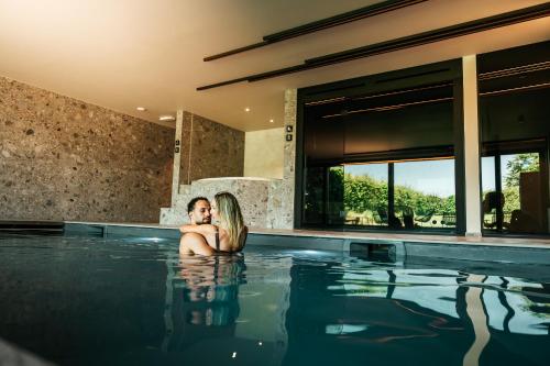 a man and a woman sitting in a swimming pool at Domaine Sur Les Sarts in Ohey