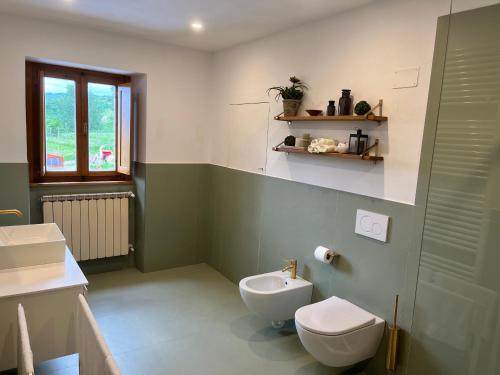 a green and white bathroom with a toilet and a sink at Vista Romena in Pratovecchio